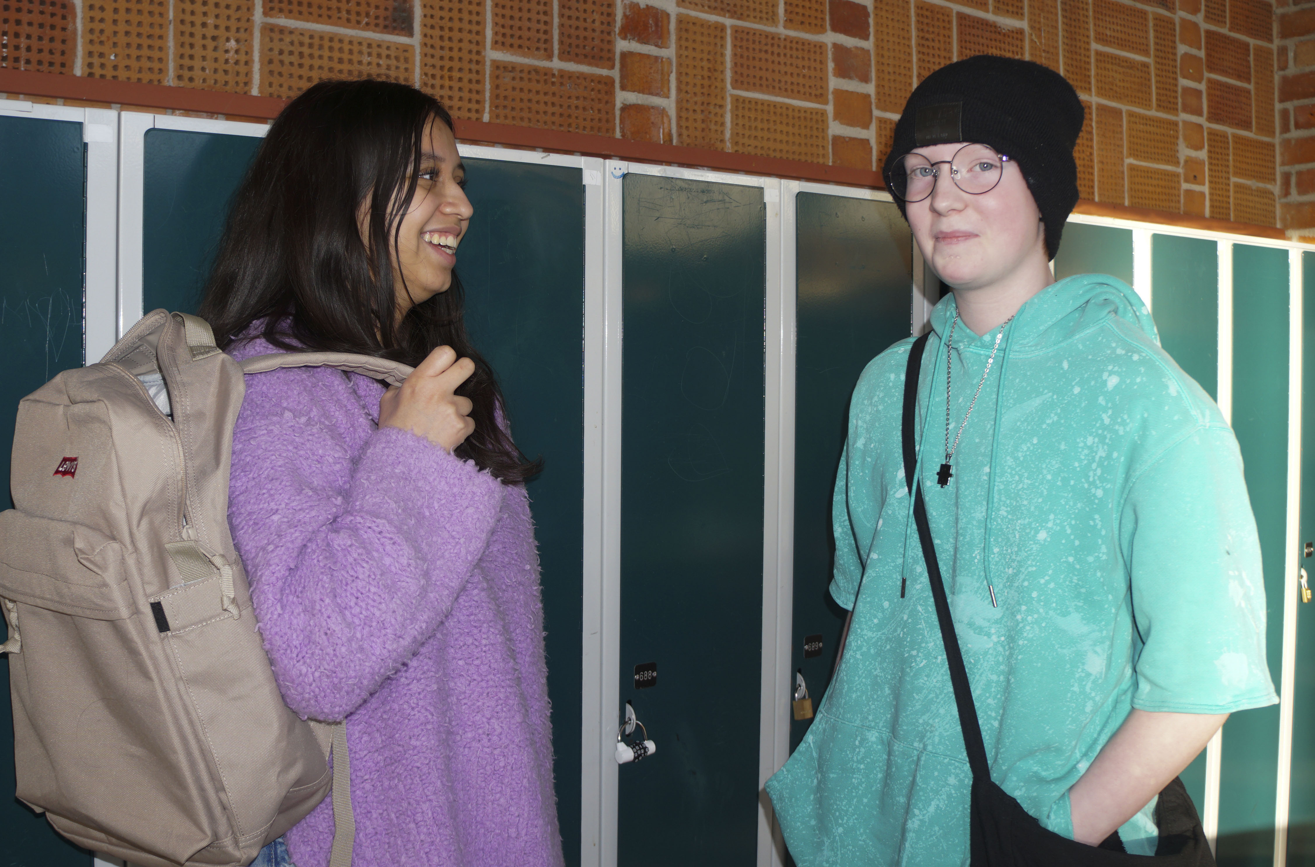 Två personer pratar och ler mot varandra i skolan.